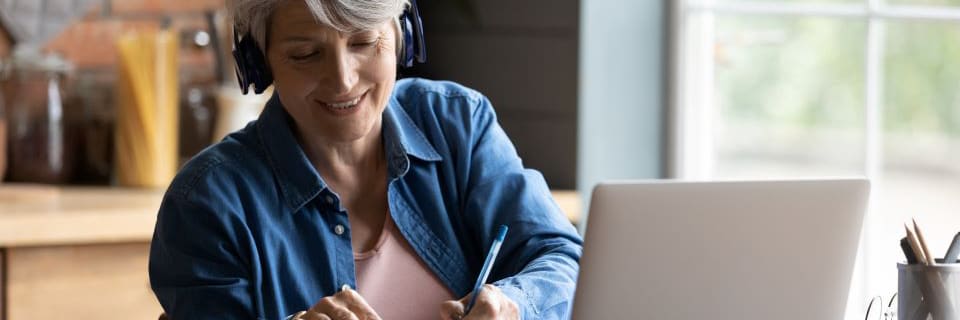 A senior woman reads assisted living reviews on a laptop