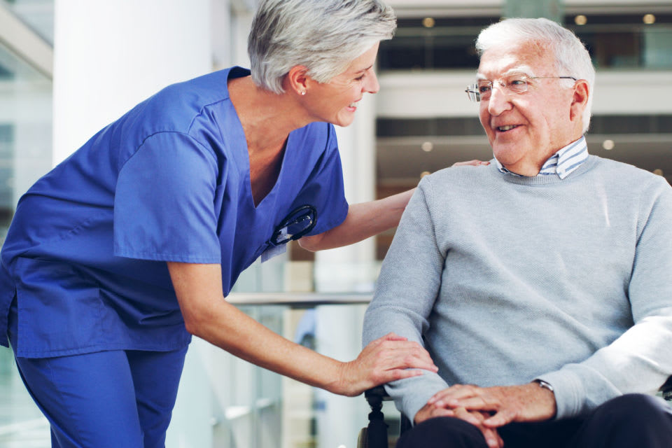 An in-home caregiver leaning in to conversation with a senior man