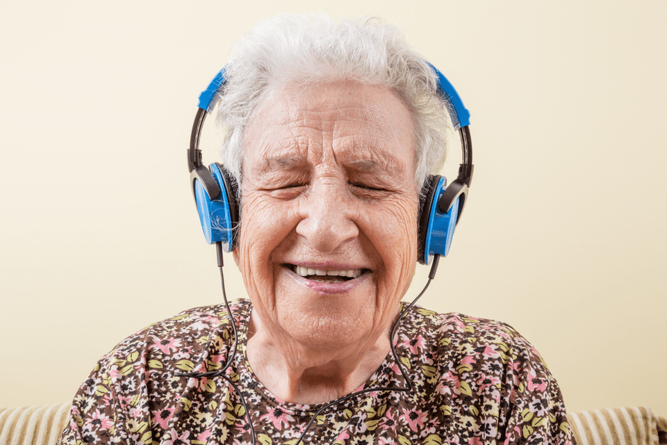 Elderly woman smiling while listening to music with headphones