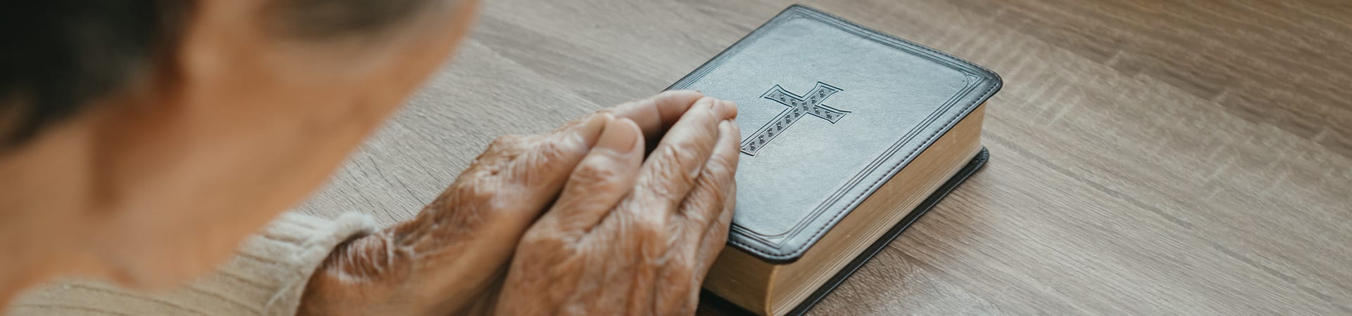 A senior prays over a bible