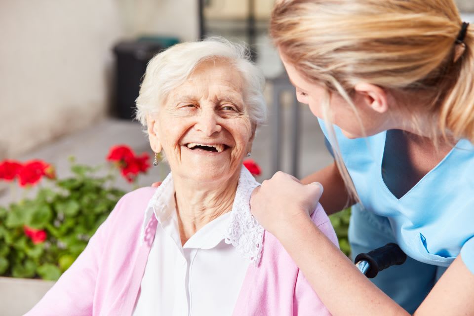 Elderly woman smiles and talks with staff at a memory care community