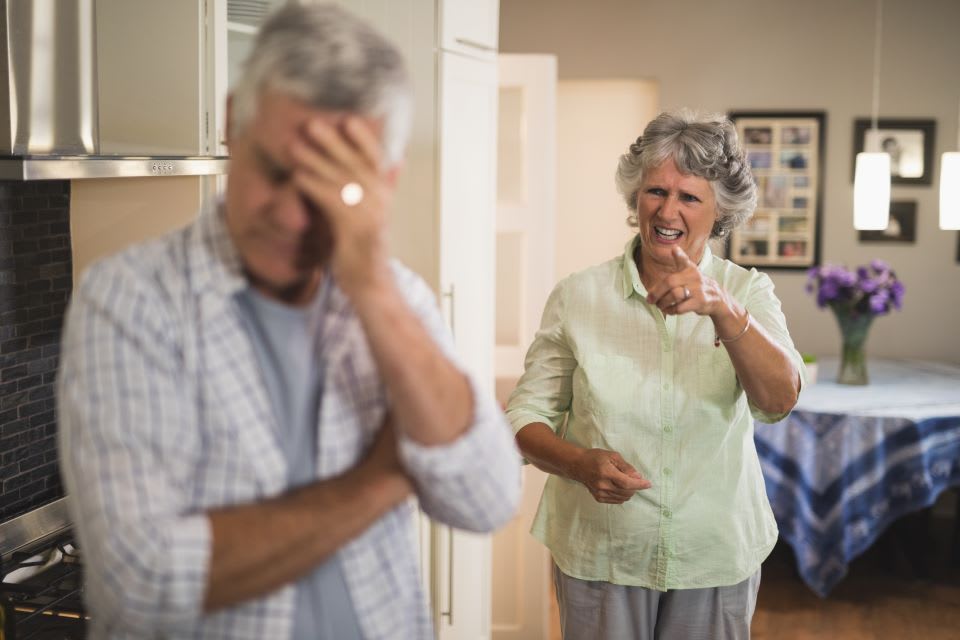 A senior woman expresses anger toward a senior man turning away in distress