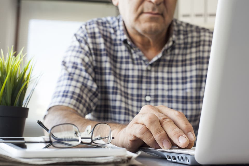 Elderly man typing at a computer.