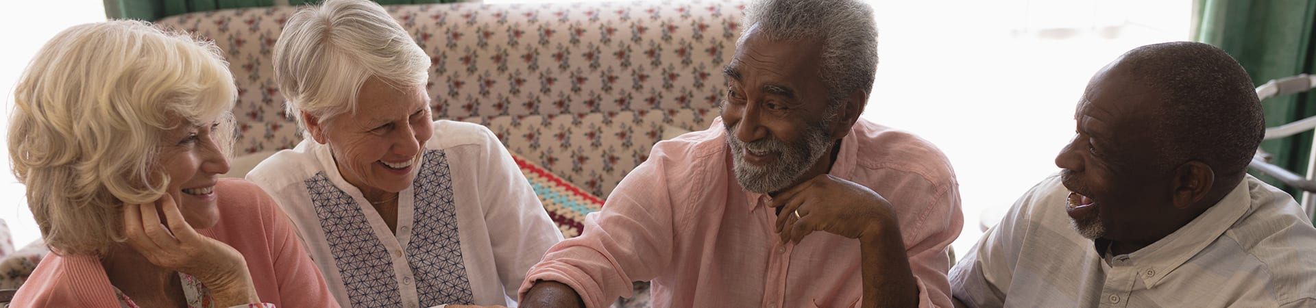 A group of seniors in long-term care smiling and laughing while in conversation