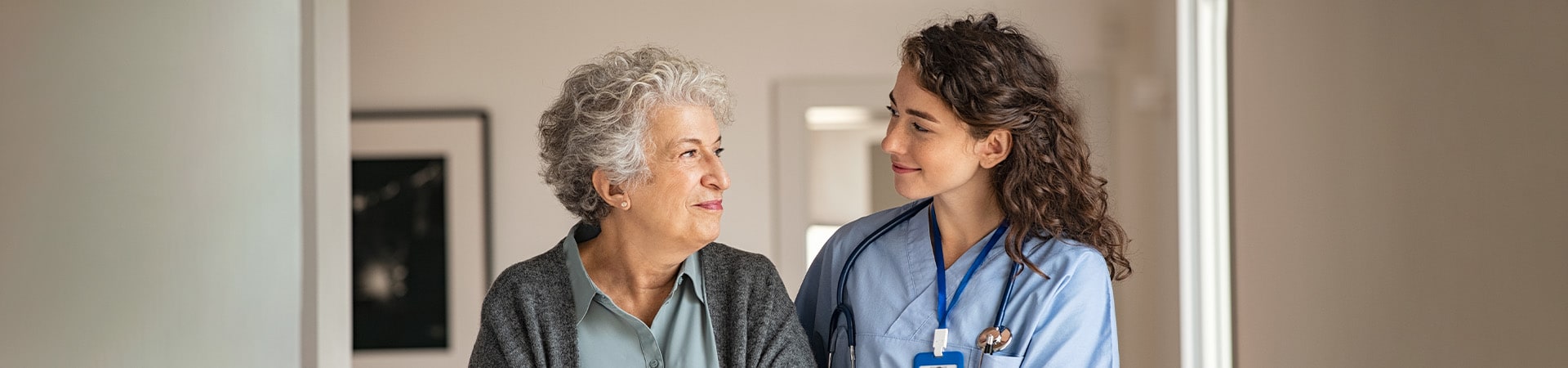 A caregiver and a senior women smile at each other